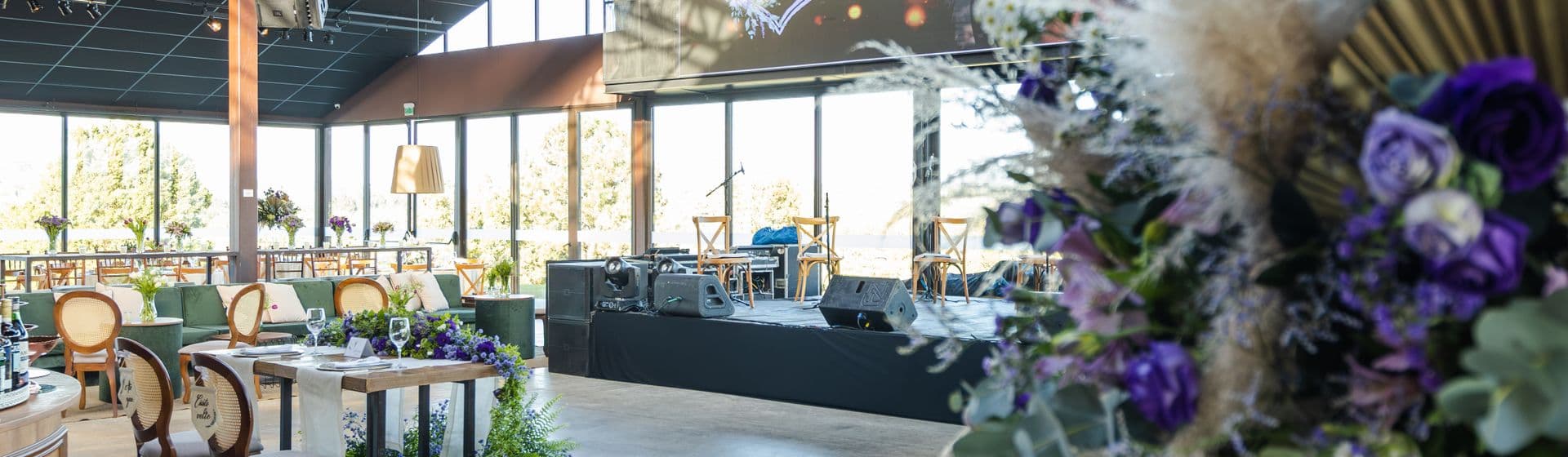 An elegant event venue set for a celebration — tables, florals, and a stage